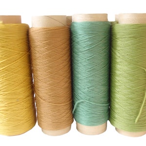 May include: Four spools of thread in yellow, brown, green, and light green colors.