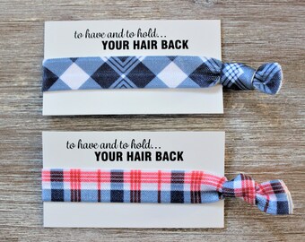 May include: Two hair ties with a plaid pattern. The hair ties are on white cards with the text "to have and to hold... YOUR HAIR BACK". One hair tie is blue and white plaid, and the other is red, blue, and white plaid.