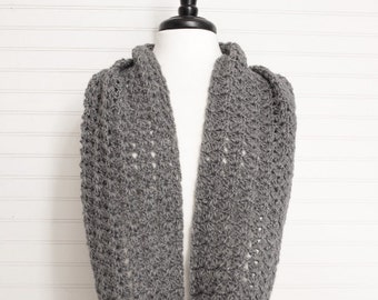 May include: A gray crocheted infinity scarf with an open stitch pattern.