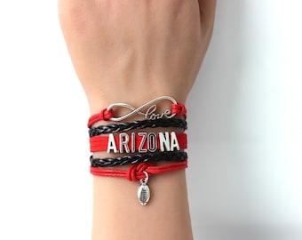 May include: A red and black layered bracelet with a silver infinity charm that says "love" and a silver charm shaped like a football. The bracelet also has a silver charm with the word "ARIZONA" on it.