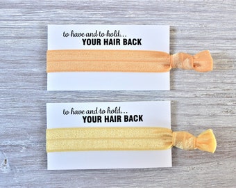 May include: Two hair ties on white cards with the text "to have and to hold... YOUR HAIR BACK". The hair ties are peach and yellow.