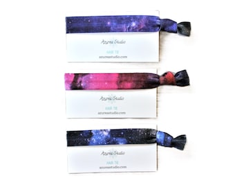 May include: Three galaxy print hair ties with a white card that reads "Azure Studio, Hair Tie, azureastudio.com".