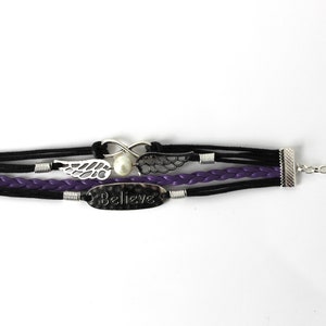 May include: A multi-strand bracelet with black and purple leather cords, silver metal accents, and a charm that says "Believe".