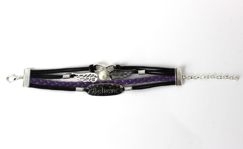 May include: A multi-strand bracelet with black and purple leather cords, silver metal accents, and a charm that says "Believe".