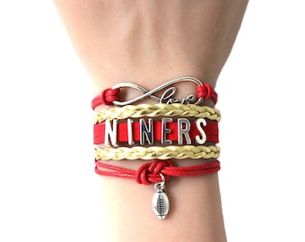 May include: Red and gold bracelet with a silver infinity charm that says "love" and a silver charm that says "NINERS" with a silver football charm.