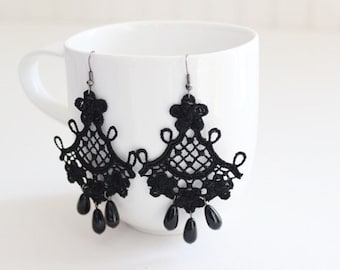 May include: Black lace chandelier earrings with teardrop beads. These elegant earrings feature a delicate, openwork design with intricate detailing. The earrings are suspended from a silver-tone hook and are displayed against a white background.
