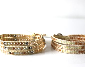 May include: Two multi-strand beaded bracelets with a cream-colored leather base. One bracelet features light brown, beige, and green beads, while the other has light brown, beige, and yellow beads.