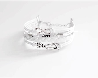 May include: White braided leather bracelet with a silver infinity symbol charm and a silver charm with the word "Love" engraved on it.