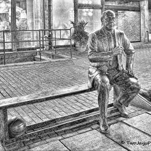 May include: A black and white photo of a bronze statue of a man sitting on a bench. The man is wearing a suit and tie and has a thoughtful expression on his face. The statue is located in a city setting.