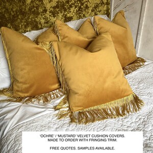 May include: Four ochre-coloured velvet cushion covers with fringing trim, arranged on a white quilted bedspread. The text on the image reads: 'OCHRE' / 'MUSTARD' VELVET CUSHION COVERS. MADE TO ORDER WITH FRINGING TRIM.