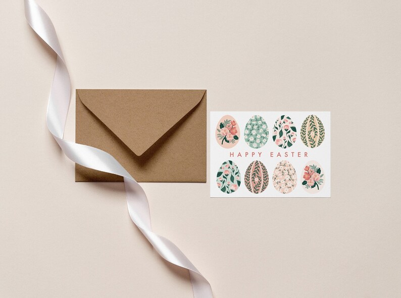 Puede incluir: Una tarjeta blanca con un dise&ntilde;o floral en ocho huevos y el texto "Feliz Pascua". La tarjeta est&aacute; junto a un sobre marr&oacute;n y una cinta blanca.