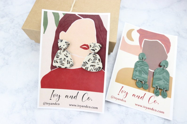 K&ouml;nnte beinhalten: Zwei Karten mit Illustrationen von Personen, die auff&auml;llige Ohrringe tragen. Die Ohrringe sind aus Polymer Clay gefertigt und haben einen Leopardenmuster und ein gr&uuml;nes Blattdesign. Die Karten zeigen den Text "Ivy and Co." und den Social-Media-Handle "@ivyandco".
