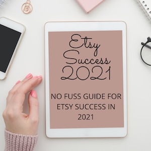 May include: A white tablet with a pink background displaying the text "Etsy Success 2021" and "No Fuss Guide for Etsy Success in 2021".