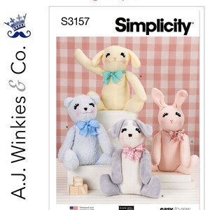 May include: Simplicity sewing pattern S3157 featuring four stuffed animal designs: a bear, a lamb, a dog, and a bunny. The pattern includes the text "Just Released" and "easy-to-sew". The A.J. Winkies & Co. logo is visible.