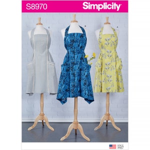 May include: Three different apron designs, each with a different pattern. The aprons are all halter style with pockets. The patterns are a light blue with a white owl print, a yellow with a white floral print, and a gray with a white lace trim.