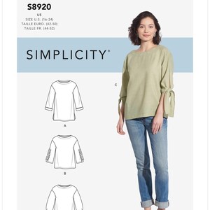 May include: A Simplicity sewing pattern, S8920, featuring a woman wearing a light green top with tie sleeves and blue jeans. The pattern includes different sleeve styles. The text "SIMPLICITY" is visible.