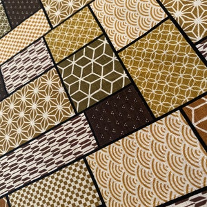 May include: A fabric with a patchwork design featuring various geometric patterns in shades of brown, green, and gold.