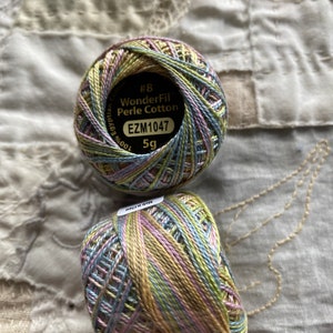 May include: Two spools of WonderFil Perle Cotton embroidery thread. The spools are green, blue, and pink. The label on the spool reads "#8 WonderFil Perle Cotton EZM1047 5g".
