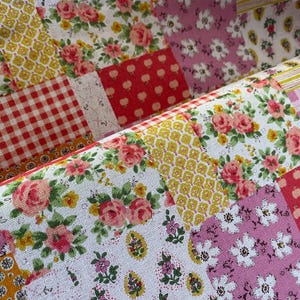 May include: Close-up of a patchwork fabric with floral and geometric patterns. The fabric features squares of red gingham, yellow honeycomb, and pink floral prints. The design is a mix of vintage and cottagecore aesthetics.