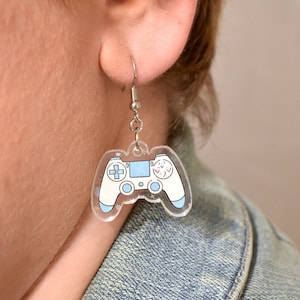 May include: A pair of silver earrings with a blue and white video game controller charm.