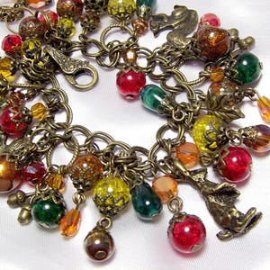May include: A vintage charm bracelet with a bronze chain and clasp. The bracelet is adorned with colorful beads in red, green, yellow, and orange, along with small bronze charms. The beads vary in size and shape, creating a unique and eye-catching accessory.