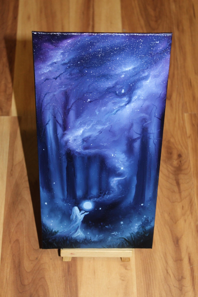 May include: A rectangular canvas painting featuring a dark blue and purple night sky filled with stars above a forest. A figure in a white robe stands in the foreground, holding a glowing white orb that emits a swirling mist into the dark trees.