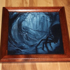 May include: A square wooden frame containing a dark, blue-toned painting of a forest scene. The artwork depicts a dense, shadowy woodland area with intricate spiderwebs draped across tree branches and a large, dark spider silhouette in the foreground.