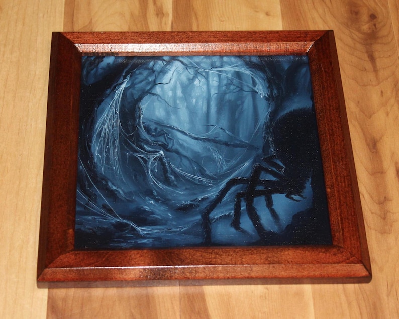 May include: A square wooden frame containing a dark, blue-toned painting of a forest scene. The artwork depicts a dense, shadowy woodland area with intricate spiderwebs draped across tree branches and a large, dark spider silhouette in the foreground.