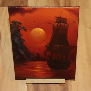 Pu&ograve; includere: Un dipinto a olio su tela che raffigura la sagoma scura di un veliero sull'acqua durante un vibrante tramonto arancione. Un grande sole luminoso &egrave; sospeso nel cielo vicino a una scogliera rocciosa con alberi di colore verde scuro.