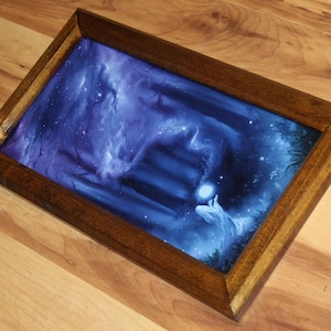May include: A rectangular wooden tray featuring a dark blue and purple fantasy illustration of a glowing orb held by a figure near stone steps. The frame is made of polished brown wood with mitered corners, surrounding the vibrant, ethereal artwork.