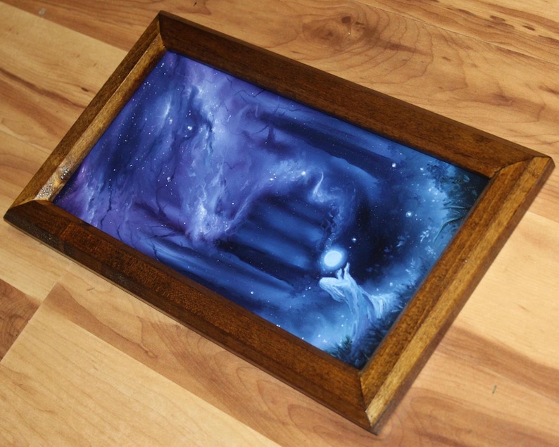 May include: A rectangular wooden tray featuring a dark blue and purple fantasy illustration of a glowing orb held by a figure near stone steps. The frame is made of polished brown wood with mitered corners, surrounding the vibrant, ethereal artwork.