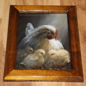 May include: Oil painting of a hen with three chicks, framed in a dark wood. The hen is white with gray shading, a red comb, and a yellow beak. The chicks are fluffy yellow. The background is dark, with light shining on the hen and chicks.
