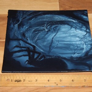 May include: A square canvas painting featuring a dark blue and black forest scene with a large spider silhouette in the foreground. A wooden ruler is placed along the bottom edge, showing the canvas width is approximately 9 inches wide.