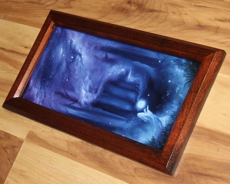 May include: A rectangular wooden frame containing a print of a dark blue, ethereal scene. The artwork depicts a glowing orb held by a figure amidst swirling blue mist and shadows, with a set of stairs leading into the deep, dark background.