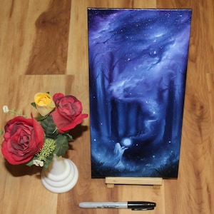 May include: A rectangular canvas painting depicting a dark forest scene with a glowing orb held by a figure, set on a small wooden easel. Beside it is a white vase containing red and yellow roses, with a black permanent marker measuring 5.25 inches.