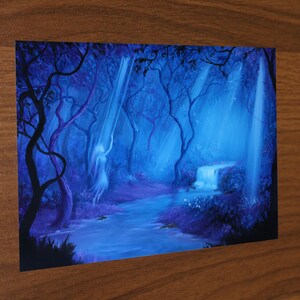 May include: A fantasy art print depicting a serene forest scene. The artwork features a flowing river, a small waterfall, and a figure bathed in ethereal light. The color palette is dominated by shades of blue and purple, creating a mystical atmosphere.