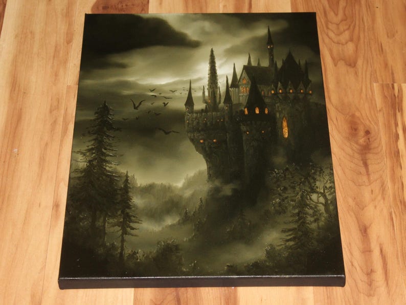 May include: A canvas print depicting a gothic castle on a cliff, illuminated by warm light from within. The artwork features a dark, moody color palette with a cloudy sky, silhouetted trees, and flying birds, creating a mysterious atmosphere.