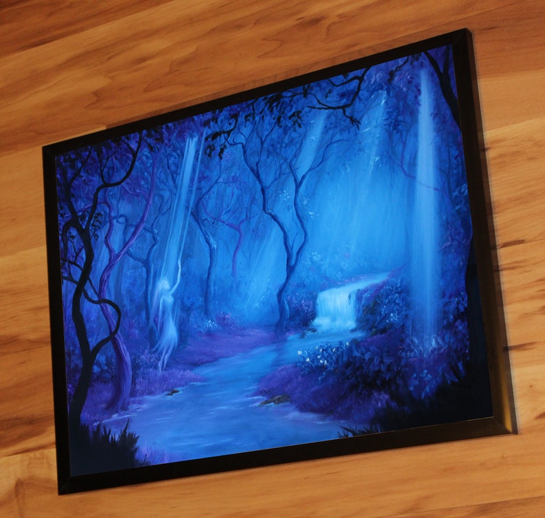 May include: Framed artwork depicting a mystical forest scene. The painting features a waterfall, a flowing river, and silhouetted trees in shades of blue and purple. A ghostly figure is visible near the waterfall. The artwork is framed in a black border.