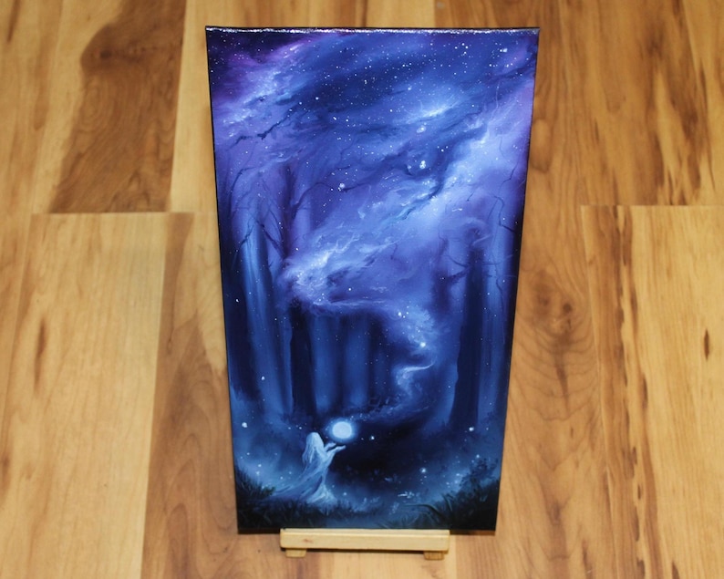May include: A rectangular canvas painting featuring a dark forest scene in shades of deep blue and purple. A figure stands in the foreground holding a glowing white orb, with swirling cosmic clouds and scattered stars filling the night sky above.