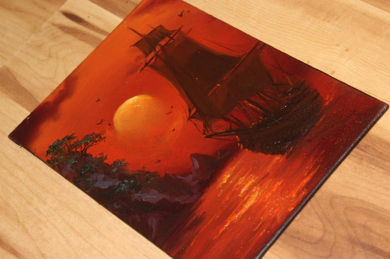 Pu&ograve; includere: Un dipinto a olio su tela che raffigura la sagoma scura di un veliero su un mare vibrante color arancione e rosso. Un grande sole giallo brillante &egrave; sospeso nel cielo sopra una costa rocciosa con alberi verde scuro, in toni caldi.