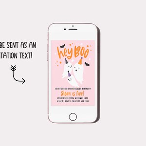 May include: A smartphone displays a pink Halloween-themed invitation with the text "hey Boo" in orange. The invitation features cartoon ghosts wearing party hats and the text "Sloan is Five!" The phone also has the text "Can be sent as an invitation text!"