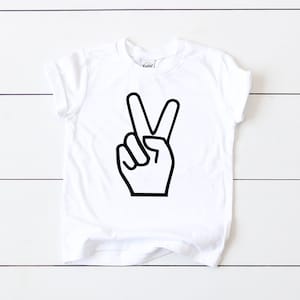 May include: White t-shirt with a black peace sign graphic.