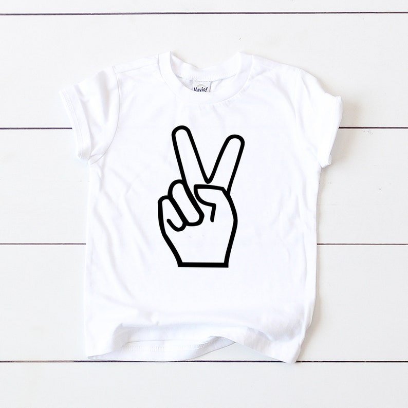 May include: White t-shirt with a black peace sign graphic.