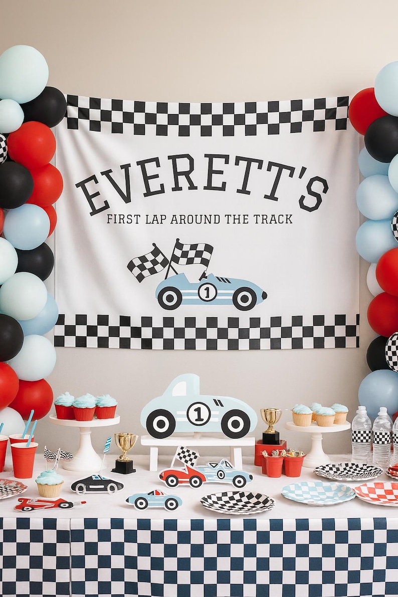 May include: A race car themed party setup with a banner that reads "Everett's First Lap Around The Track". The scene includes balloons, cupcakes, and race car decorations. The color scheme is red, black, white, and light blue.