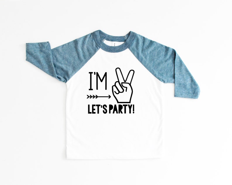 May include: White and blue long-sleeved shirt with a peace sign and the text "I'M LET'S PARTY!" printed on the front.
