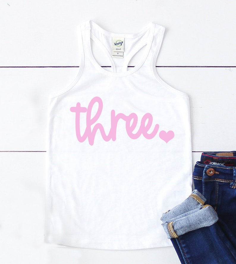 Puede incluir: Camiseta blanca de tirantes con un 'tres' rosa y un coraz&oacute;n rosa en la parte delantera.