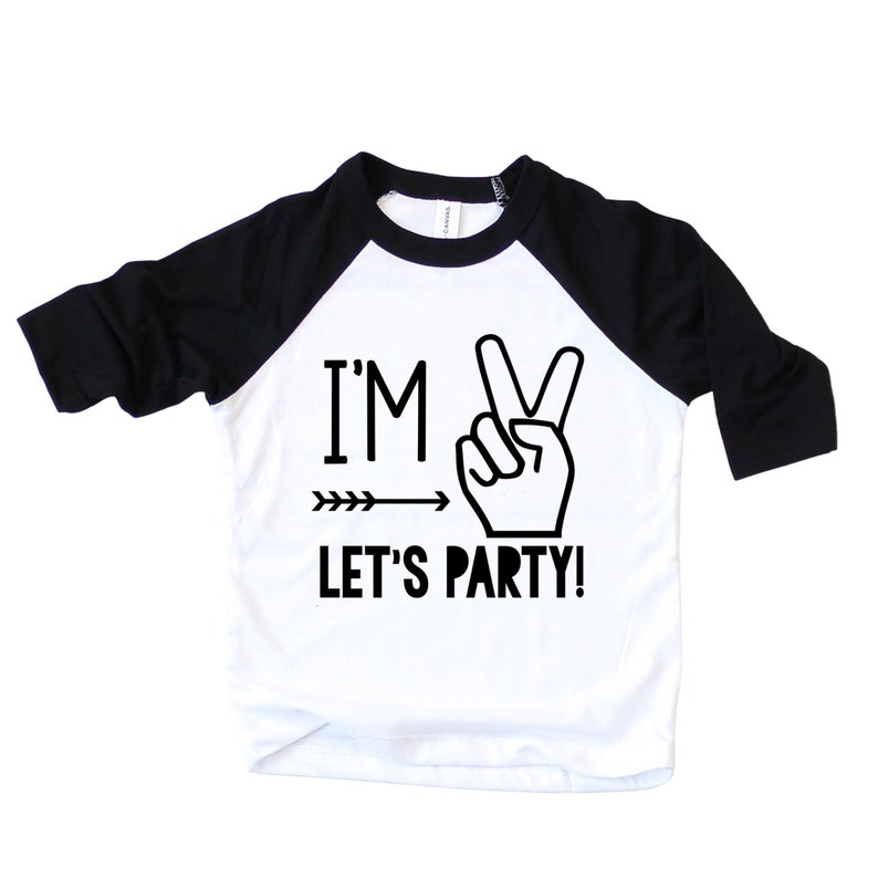 May include: A white and black baseball tee shirt with a black and white graphic that says "I'm 2 Let's Party!" with a peace sign and an arrow.