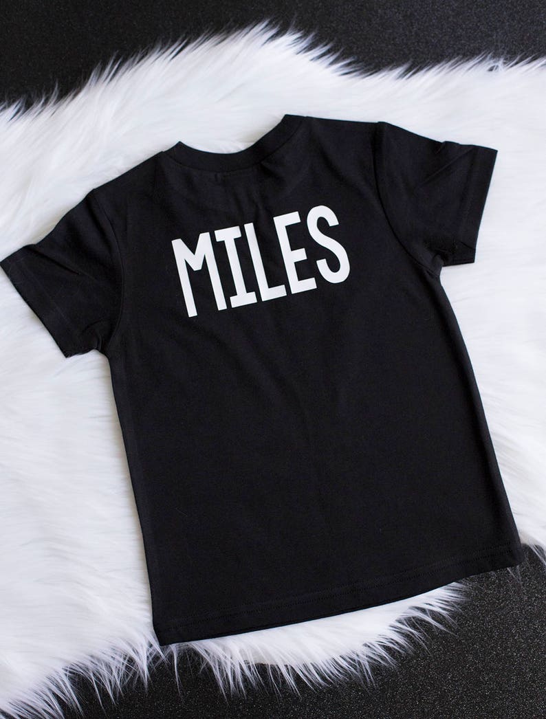 May include: Black t-shirt with the word "MILES" printed in white on the back.