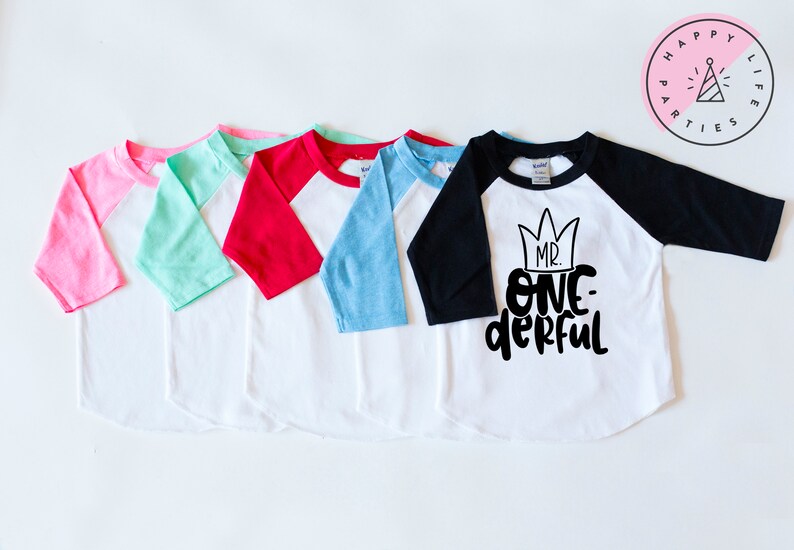 May include: Five baseball style shirts with different colored sleeves. The shirts are white with a black design that says "Mr. One-derful" with a crown above the text.