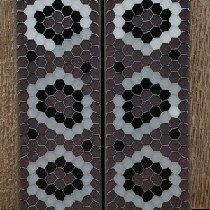 May include: Two rectangular decorative tiles with a geometric pattern. The tiles feature a dark brown background with a honeycomb design in a silver wire mesh. The honeycomb cells are filled with black and white hexagonal shapes.